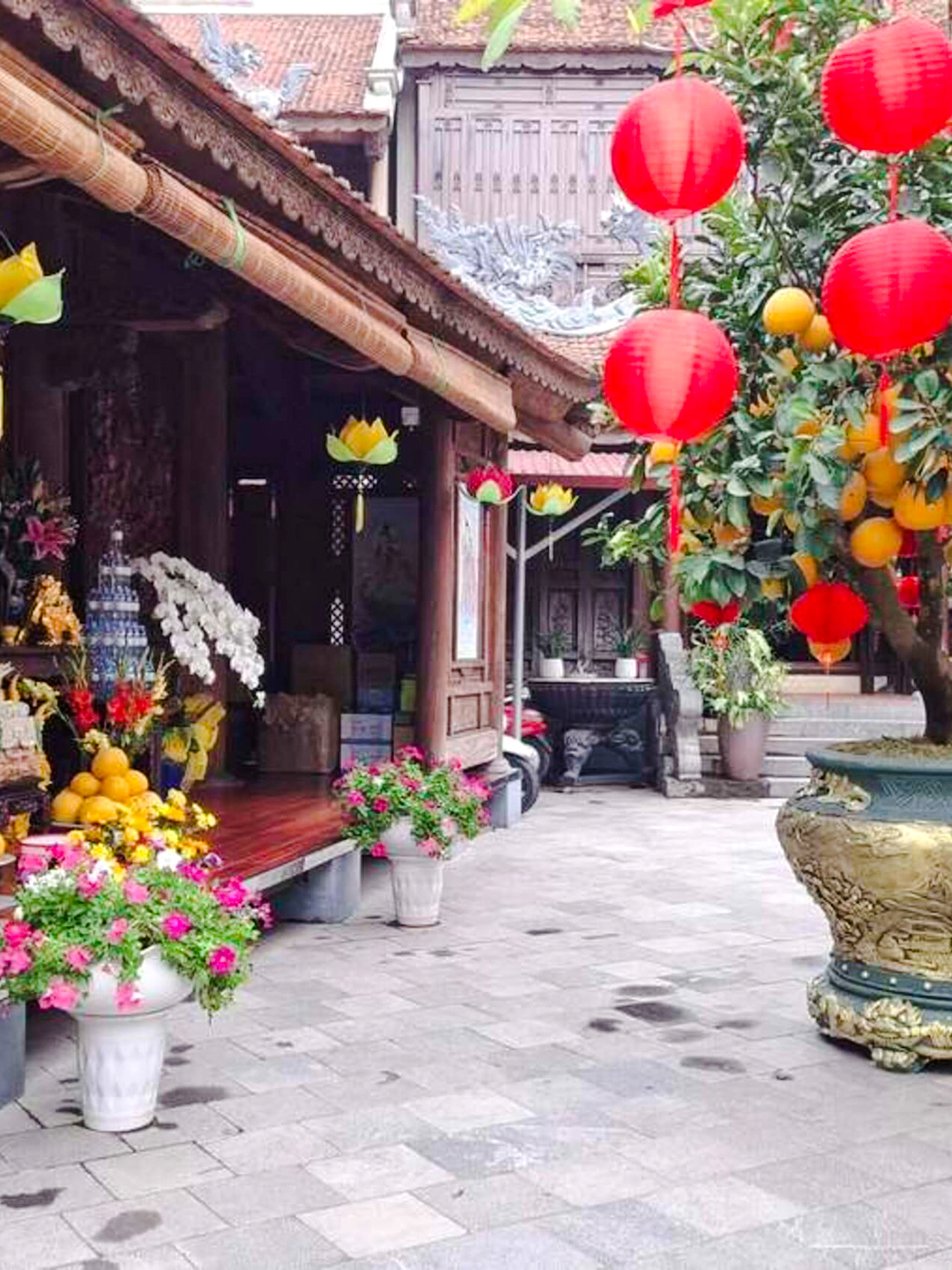 Pagoda courtyard with red lanterns and fruit offerings, Hanoi Vegan Cooking Class.