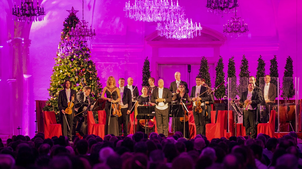 Orchestra performing at Schonbrunn Palace concert with festive decorations.