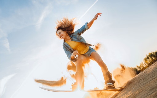Person sandboarding on a dune during a desert safari in Dubai.