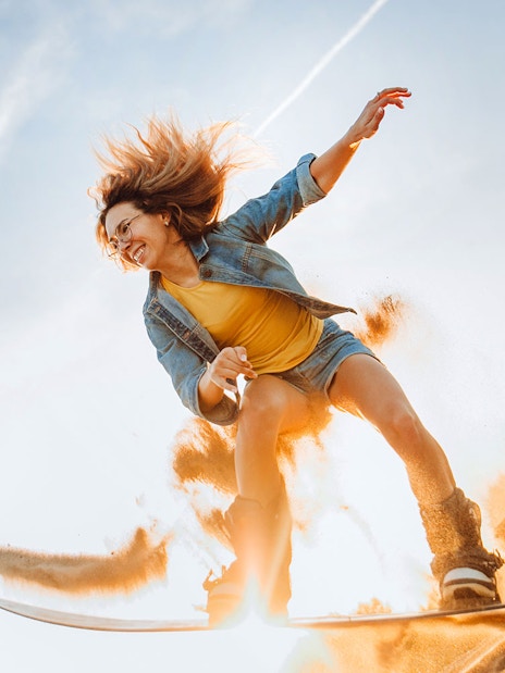 Person sandboarding on a dune during a desert safari in Dubai.