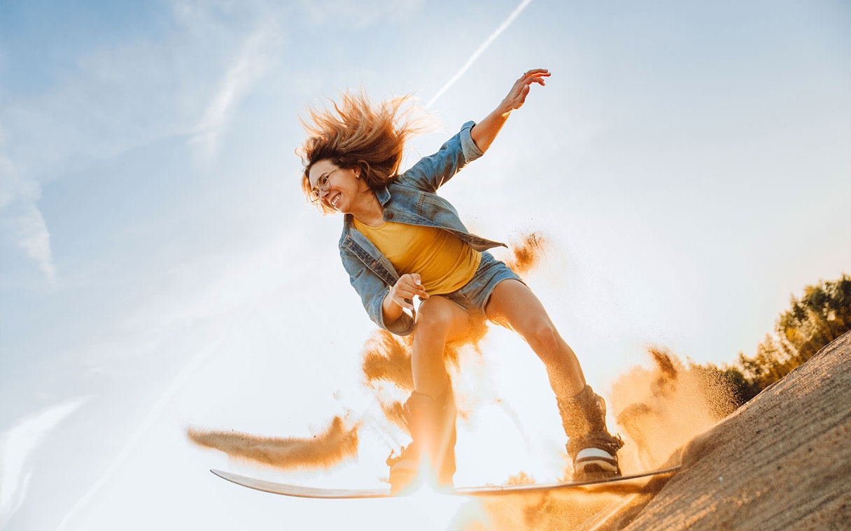 Person sandboarding on a dune during a desert safari in Dubai.