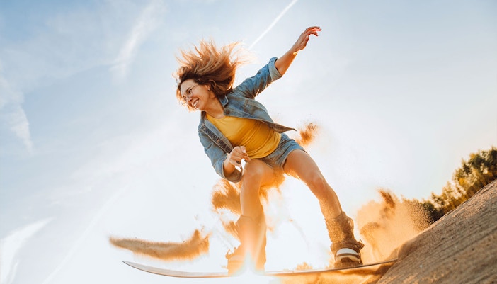 Person sandboarding on a dune during a desert safari in Dubai.
