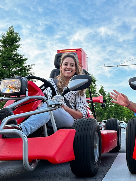 Two people smiling in red go-karts during a Shibuya street go-kart experience.