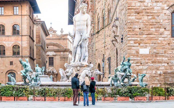 Neptune Fountain in Piazza della Signoria, Florence, with tourists observing.