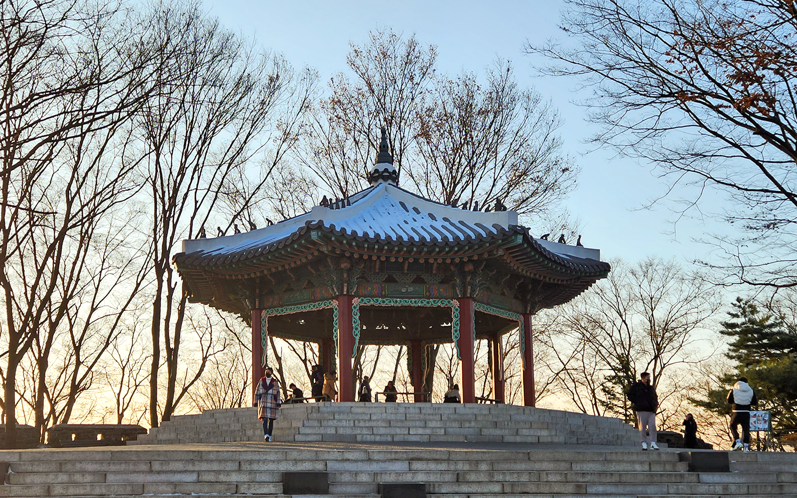 Namsan Palgakjeong pavilion surrounded by bare trees at sunset in Seoul, South Korea.