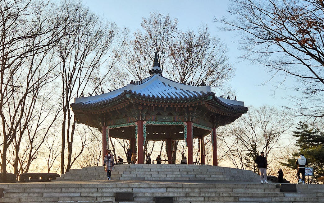 Namsan Palgakjeong pavilion surrounded by bare trees at sunset in Seoul, South Korea.