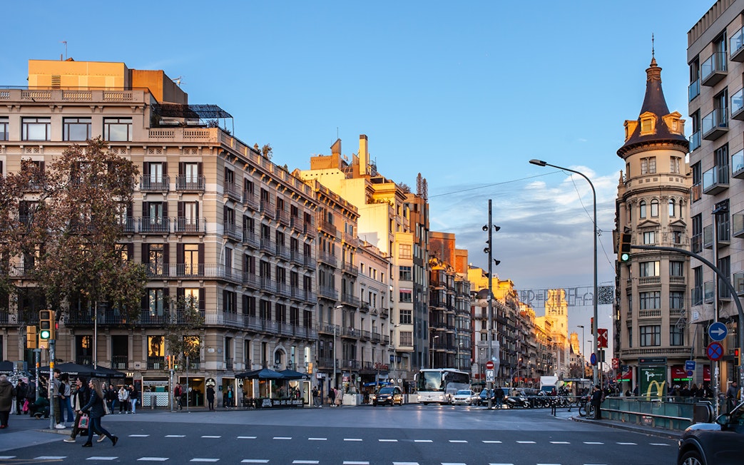 Street view of Raval district in downtown Barcelona with historic buildings and pedestrians.