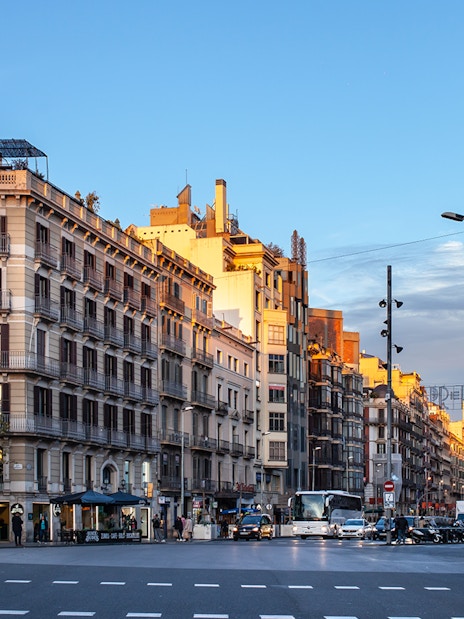 Street view of Raval district in downtown Barcelona with historic buildings and pedestrians.