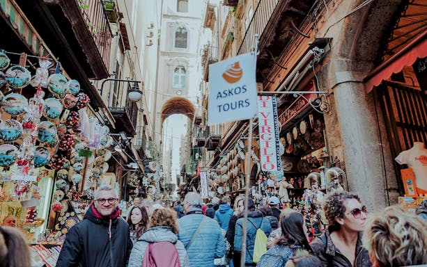 Crowded street market in Naples with tourists exploring local shops and souvenirs.