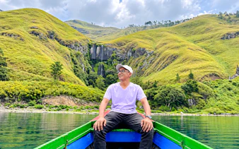 Boat trip on Lake Toba with view of waterfalls and lush hills, Medan day tour.