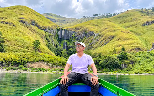 Boat trip on Lake Toba with view of waterfalls and lush hills, Medan day tour.