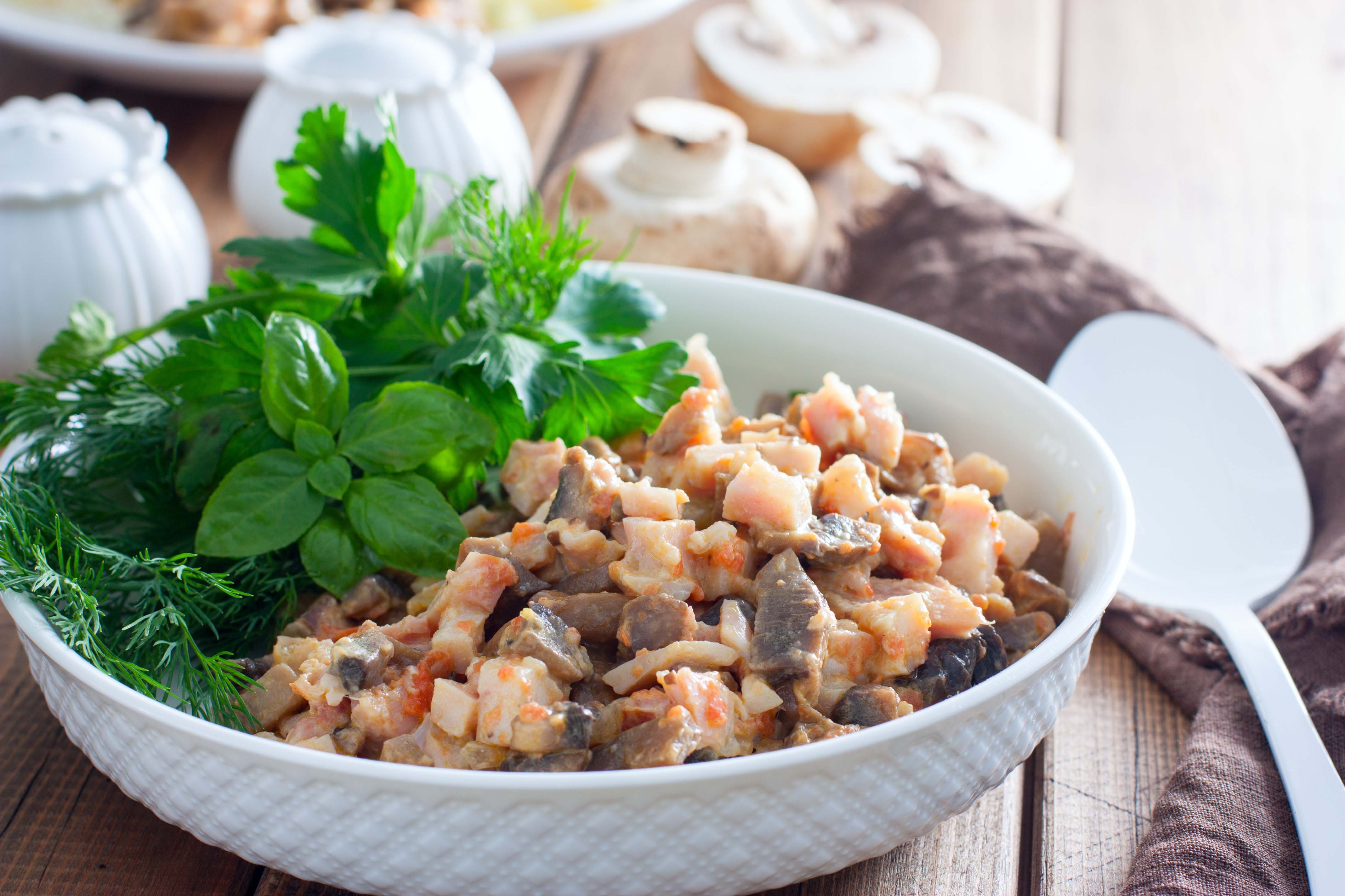 Chopped smoked chicken salad with mushrooms and fresh herbs in a white bowl.