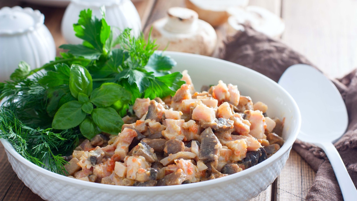 Chopped smoked chicken salad with mushrooms and fresh herbs in a white bowl.