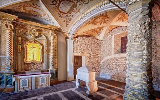 Capela dos Ossos interior with bone-adorned walls and ornate altar, Évora, Portugal.
