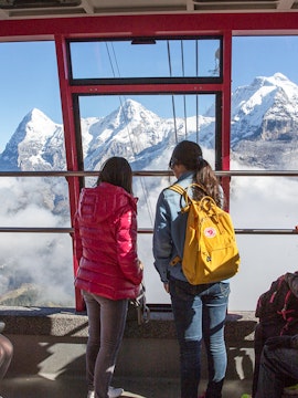 Two people in a cable car viewing the Swiss Alps with a Swiss Travel Pass.