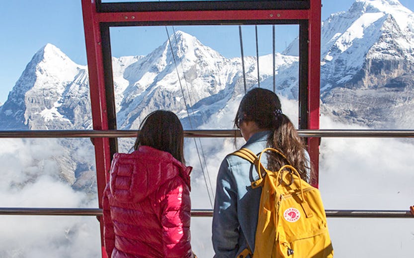 Two people in a cable car viewing the Swiss Alps with a Swiss Travel Pass.