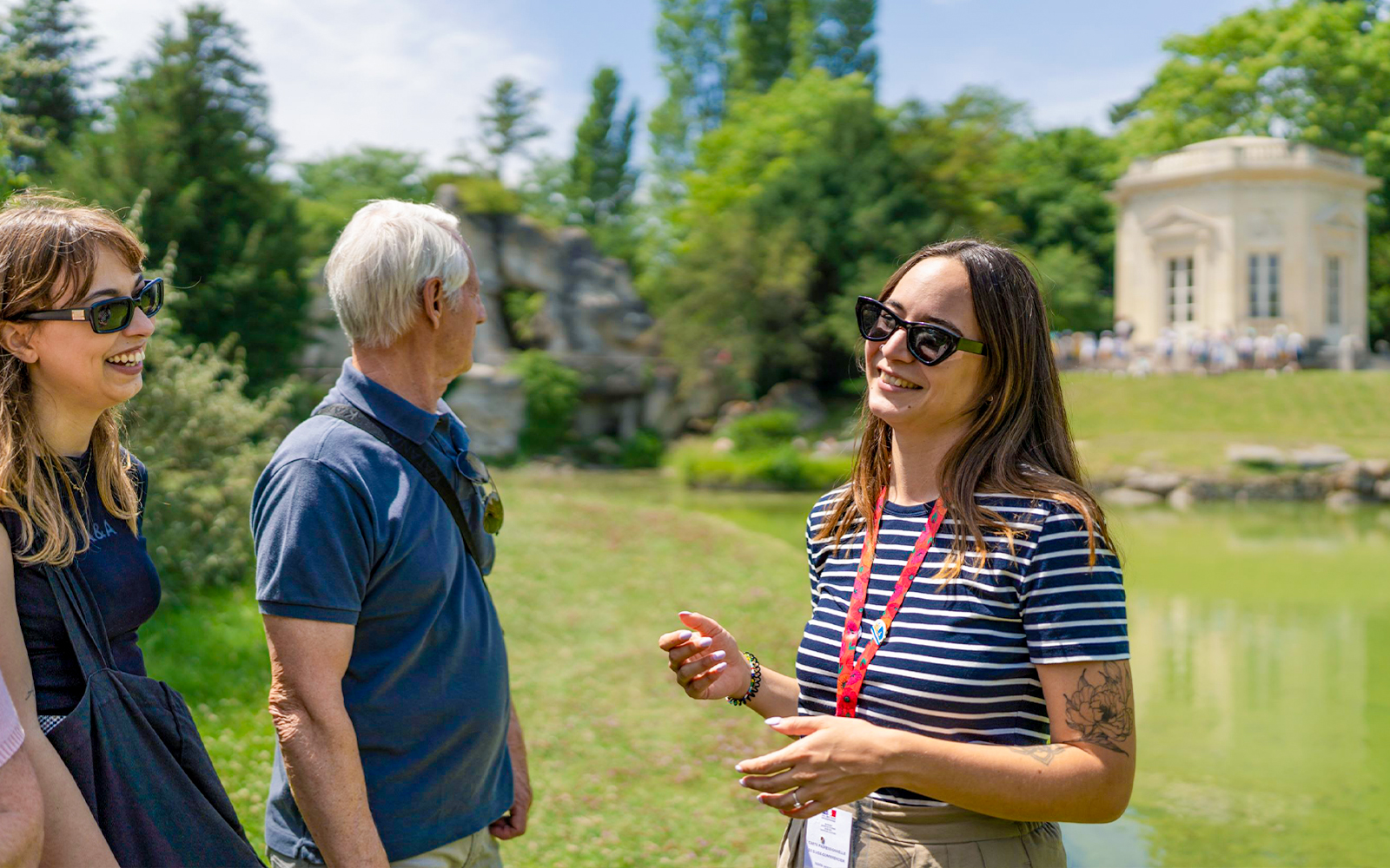 Tour guide explaining Petit Trianon to tourists in Versailles garden.
