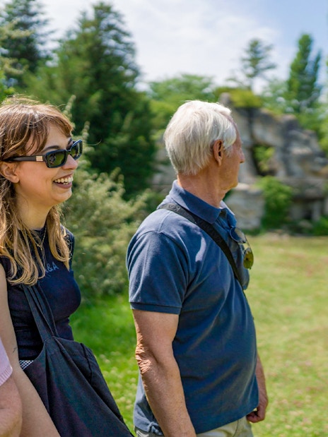 Tour guide explaining Petit Trianon to tourists in Versailles garden.