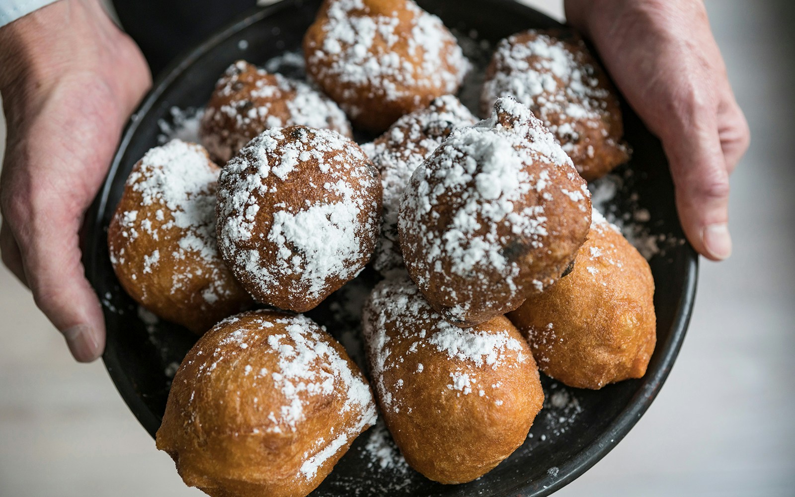 Oliebollen pastries on a plate, a traditional Dutch treat enjoyed in Amsterdam in December.