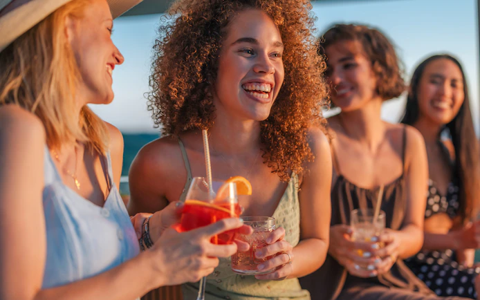 Friends enjoying cocktails at sunset on a terrace.