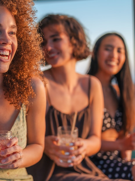 Friends enjoying cocktails at sunset on a terrace.