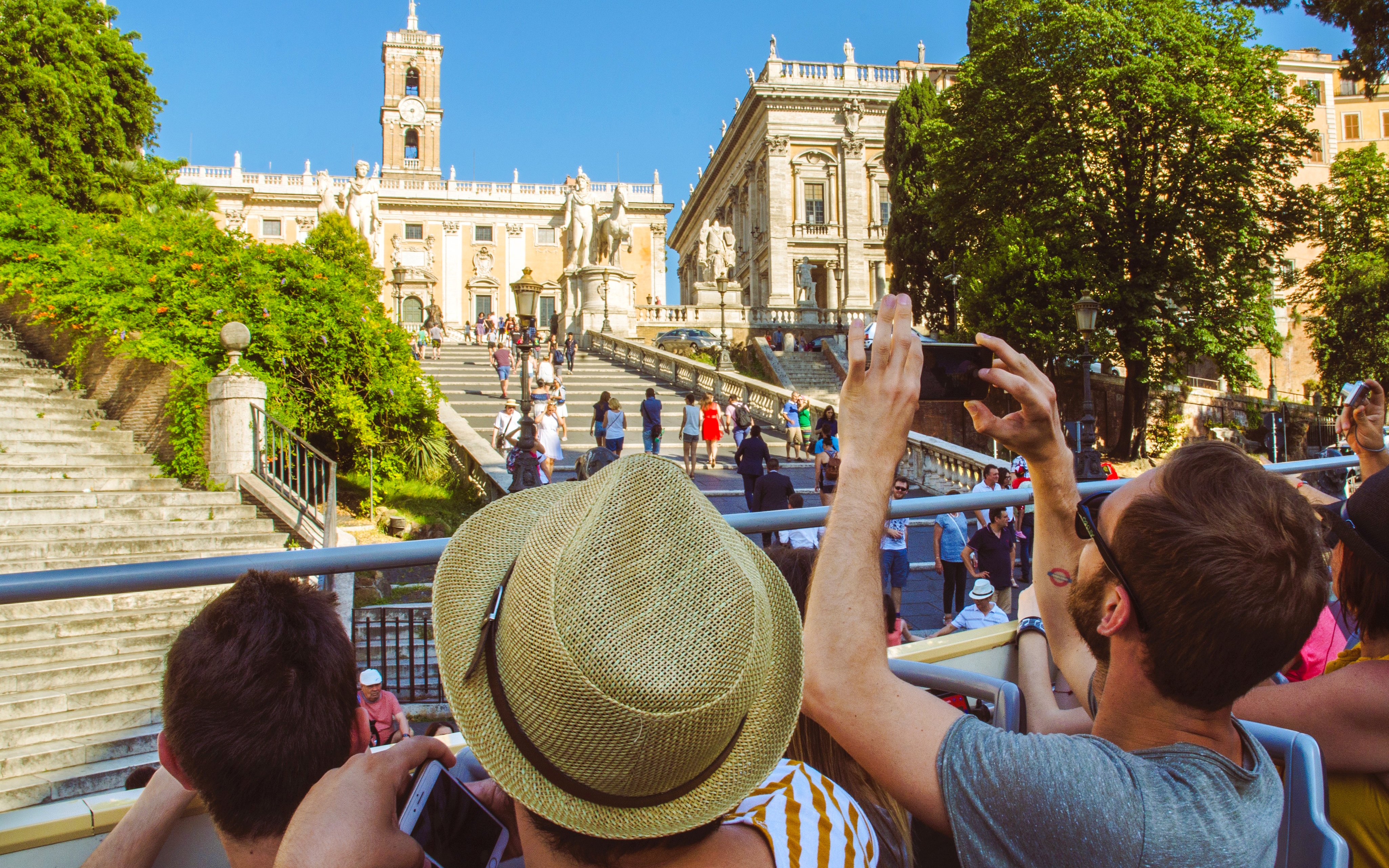Tourists on HOHO bus capturing photos of Capitoline Hill, Rome.