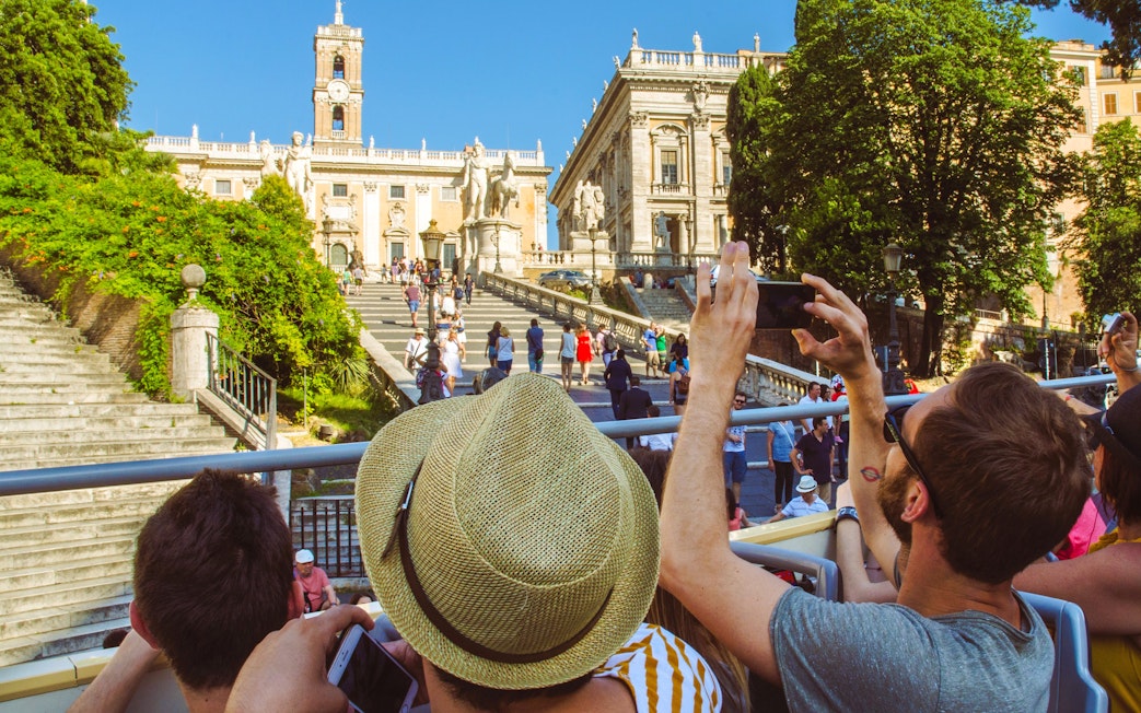 Tourists on HOHO bus capturing photos of Capitoline Hill, Rome.