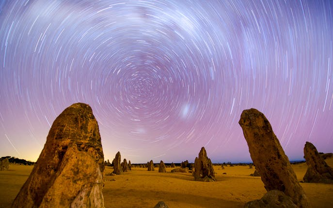 Star trails over limestone formations at Pinnacles Desert during sunset and stargazing tour.