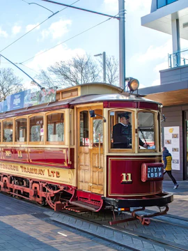 Christchurch city tram on tracks in New Zealand with driver inside.
