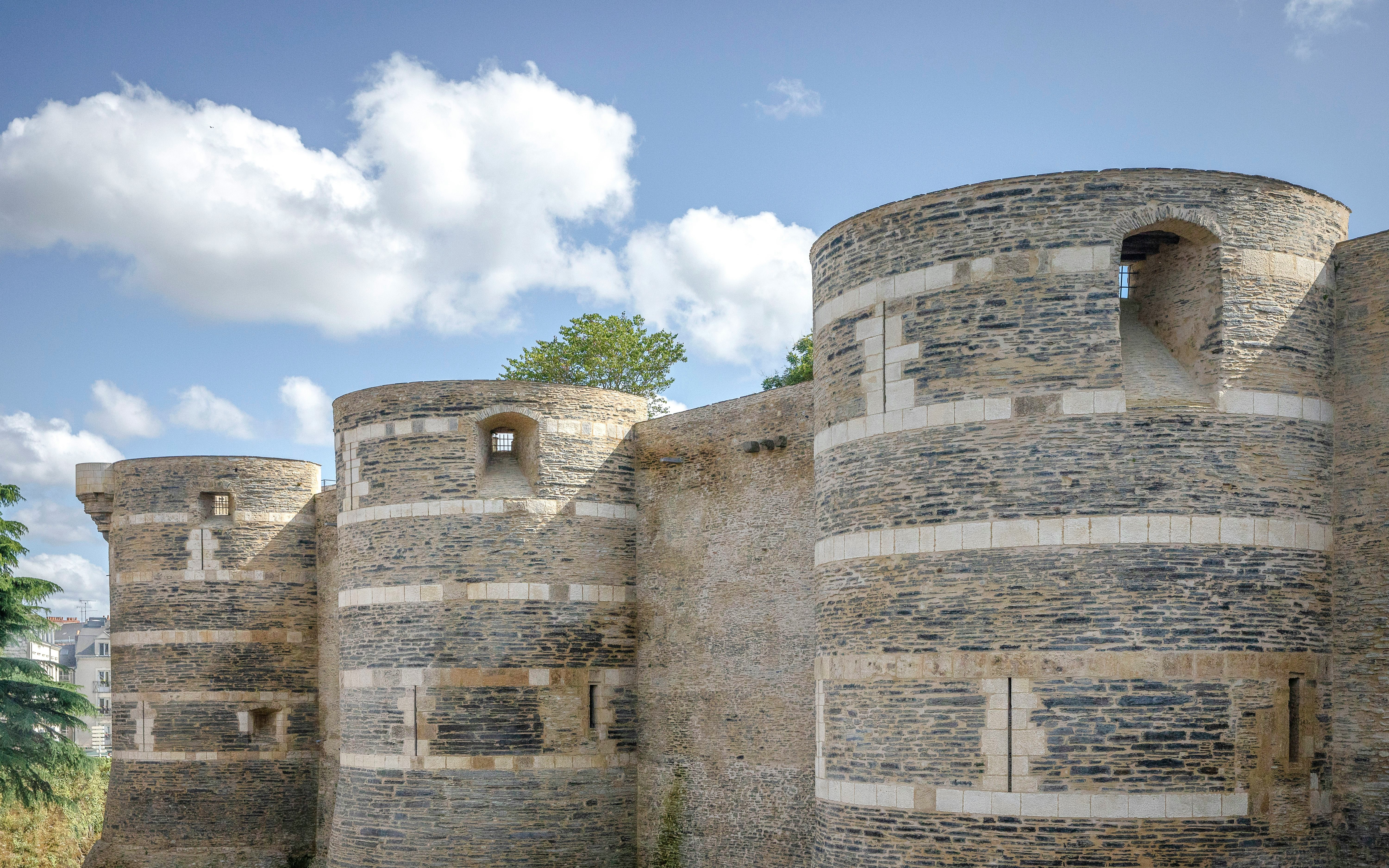 Château d’Angers stone towers under a blue sky in Angers, France.