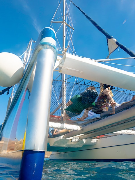 People relaxing on a catamaran net during a whale and dolphin watching cruise.