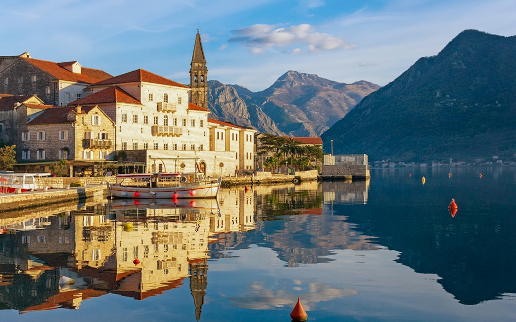 Perast town waterfront with historic buildings and mountains in Montenegro.