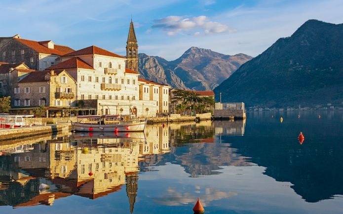 Perast town waterfront with historic buildings and mountains in Montenegro.