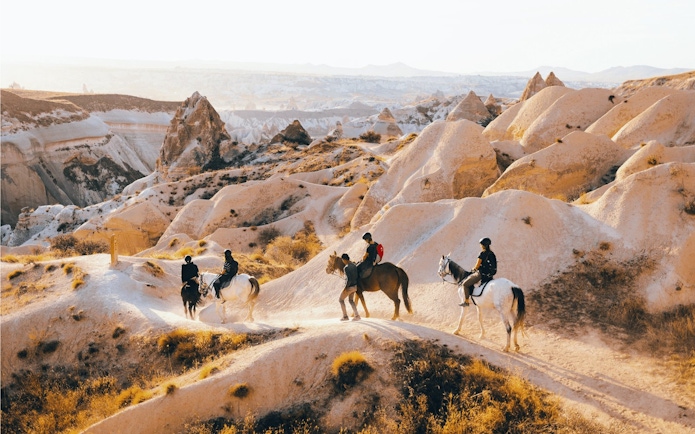 Guests horseback riding through Cappadocia's unique rock formations.