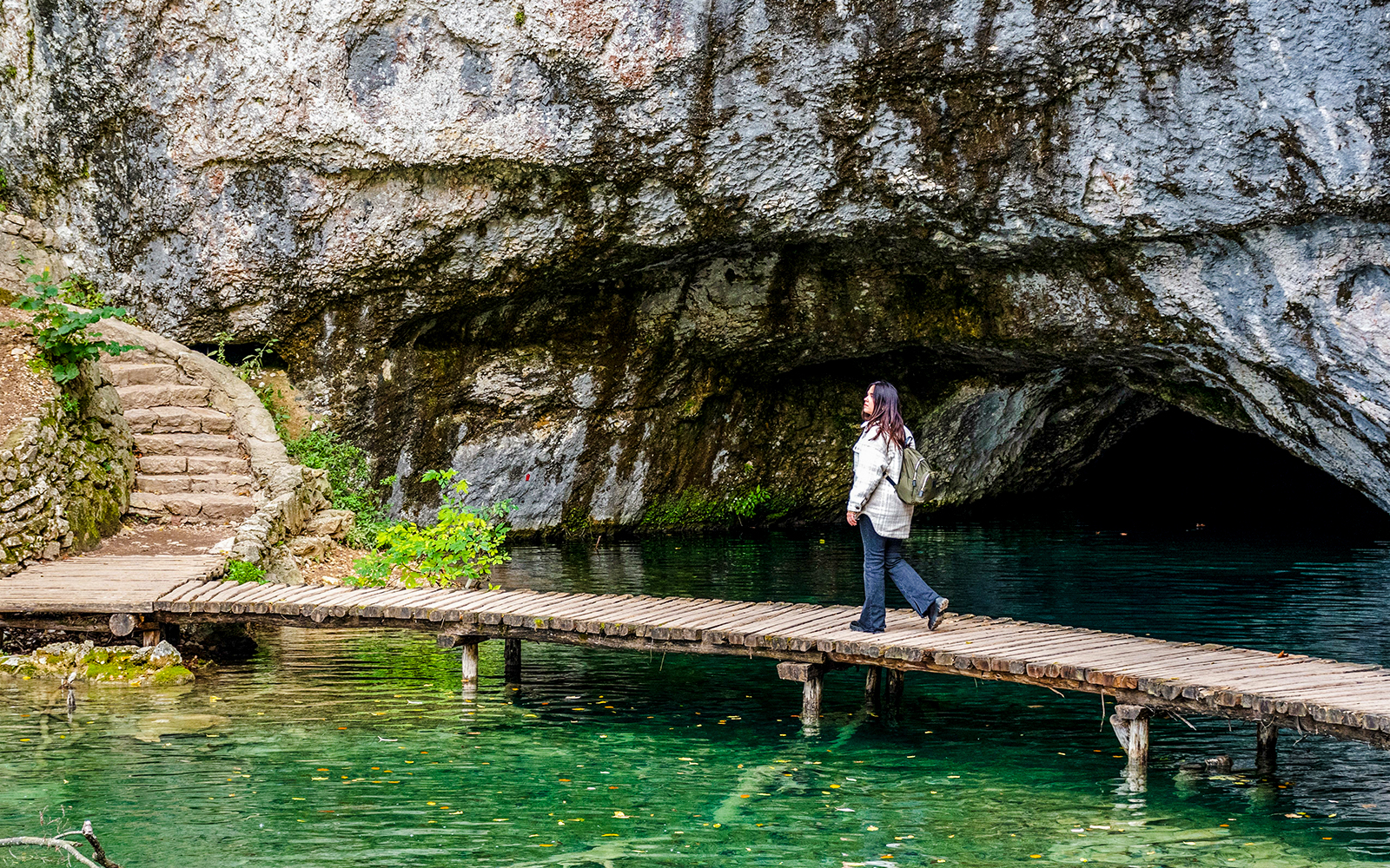 Female walking on wooden deck over turquoise water at Plitvice Lakes, Croatia.