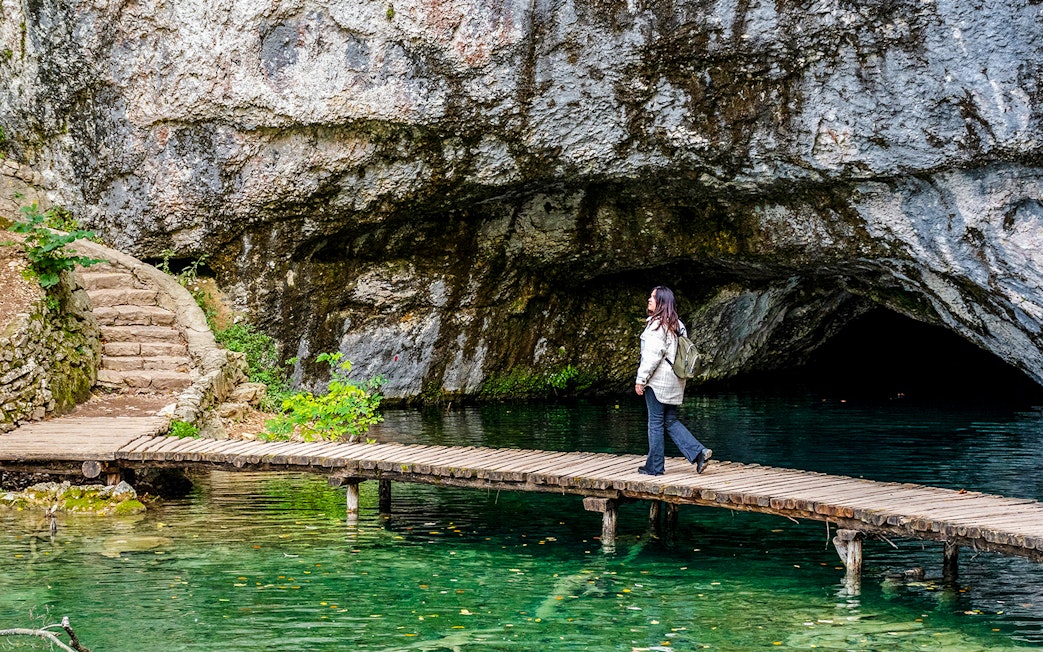 Female walking on wooden deck over turquoise water at Plitvice Lakes, Croatia.