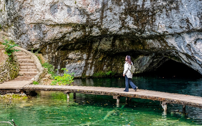 Female walking on wooden deck over turquoise water at Plitvice Lakes, Croatia.