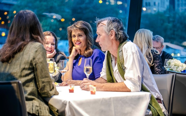 Guests enjoying a meal on a Chicago dinner cruise with city lights in the background.
