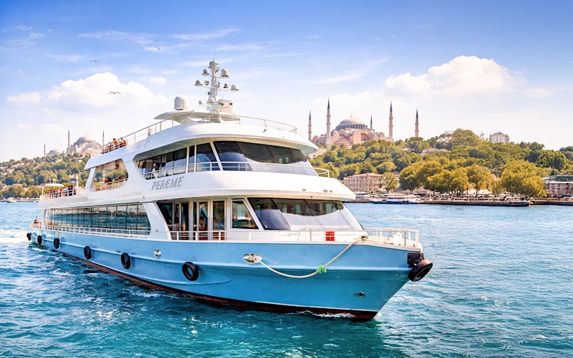 Cruise ship on Bosphorus with Hagia Sophia in Istanbul background.