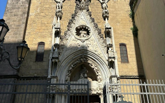 Gothic church facade with intricate stone carvings in Naples, part of self-guided city exploration game.