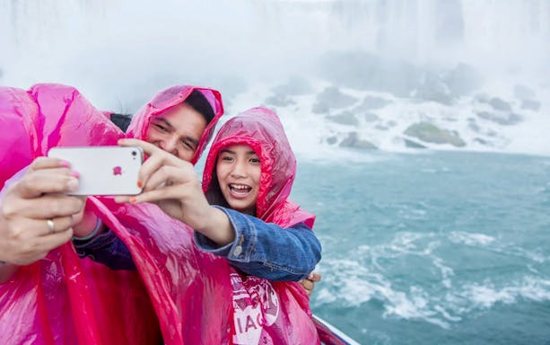 People in pink ponchos taking a selfie on a boat near Niagara Falls.