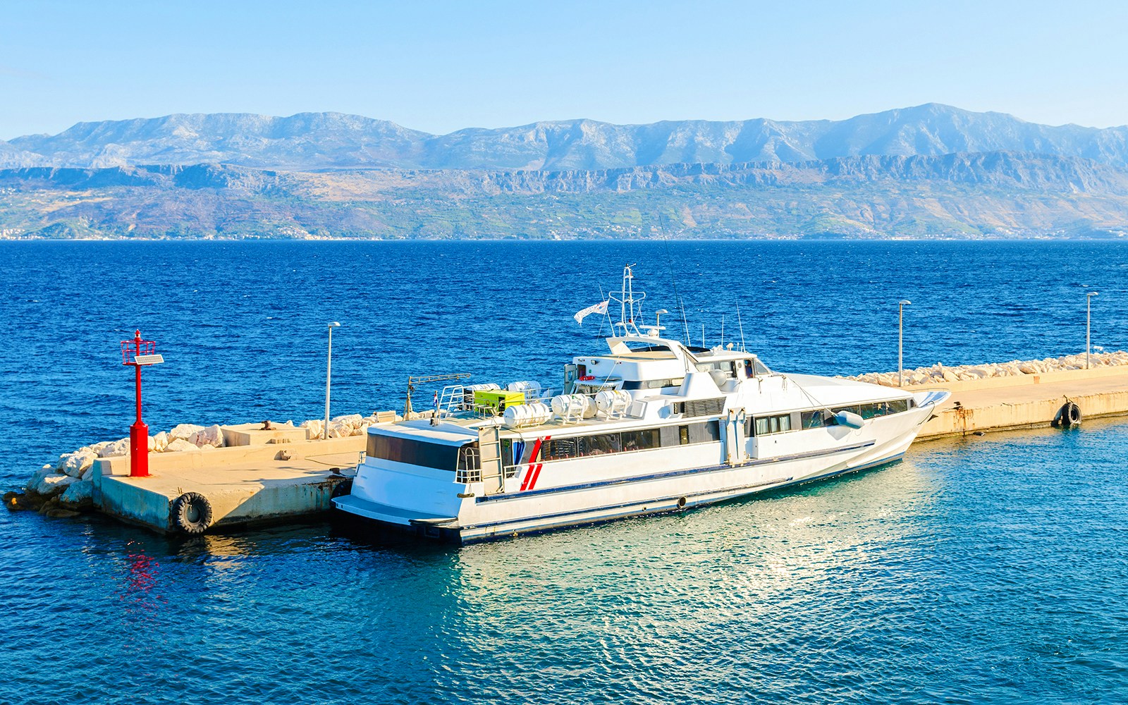 Tourist ferry ship docked at a pier with mountains in the background, Croatia.
