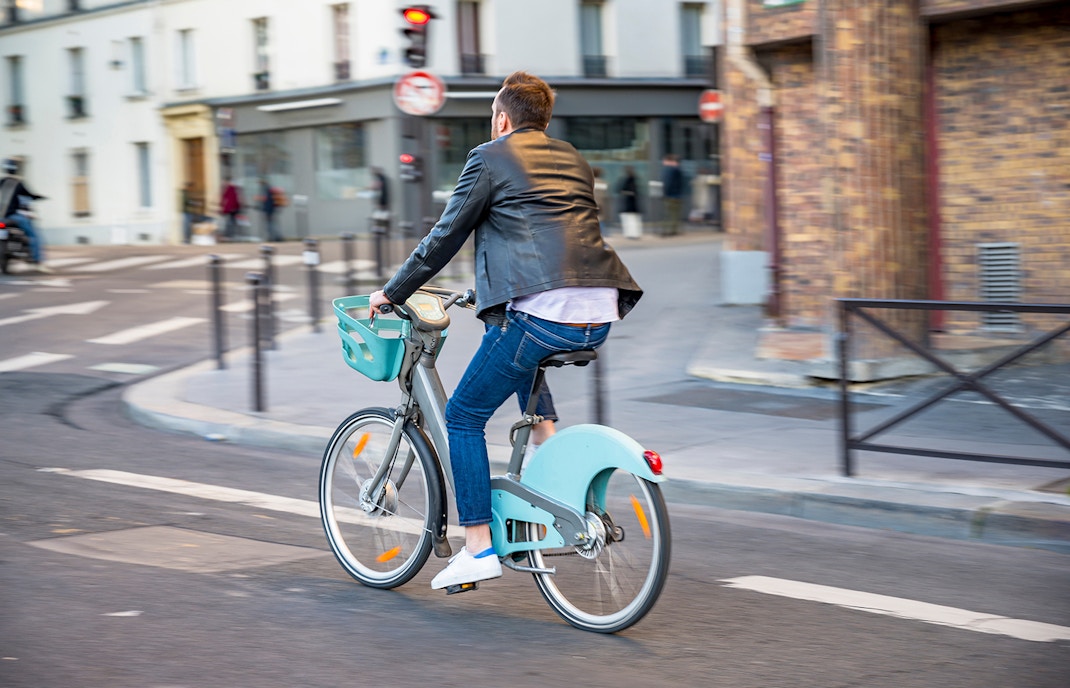 A man riding a green Velib bicycle to Pantheon.