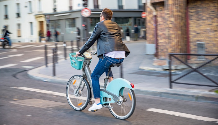 Man cycling on a Vélib' bike in Paris street.