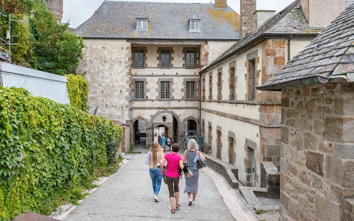 Visitors walking through Mont Saint-Michel's historic stone archway.