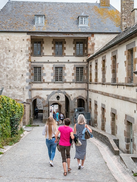 Visitors walking through Mont Saint-Michel's historic stone archway.