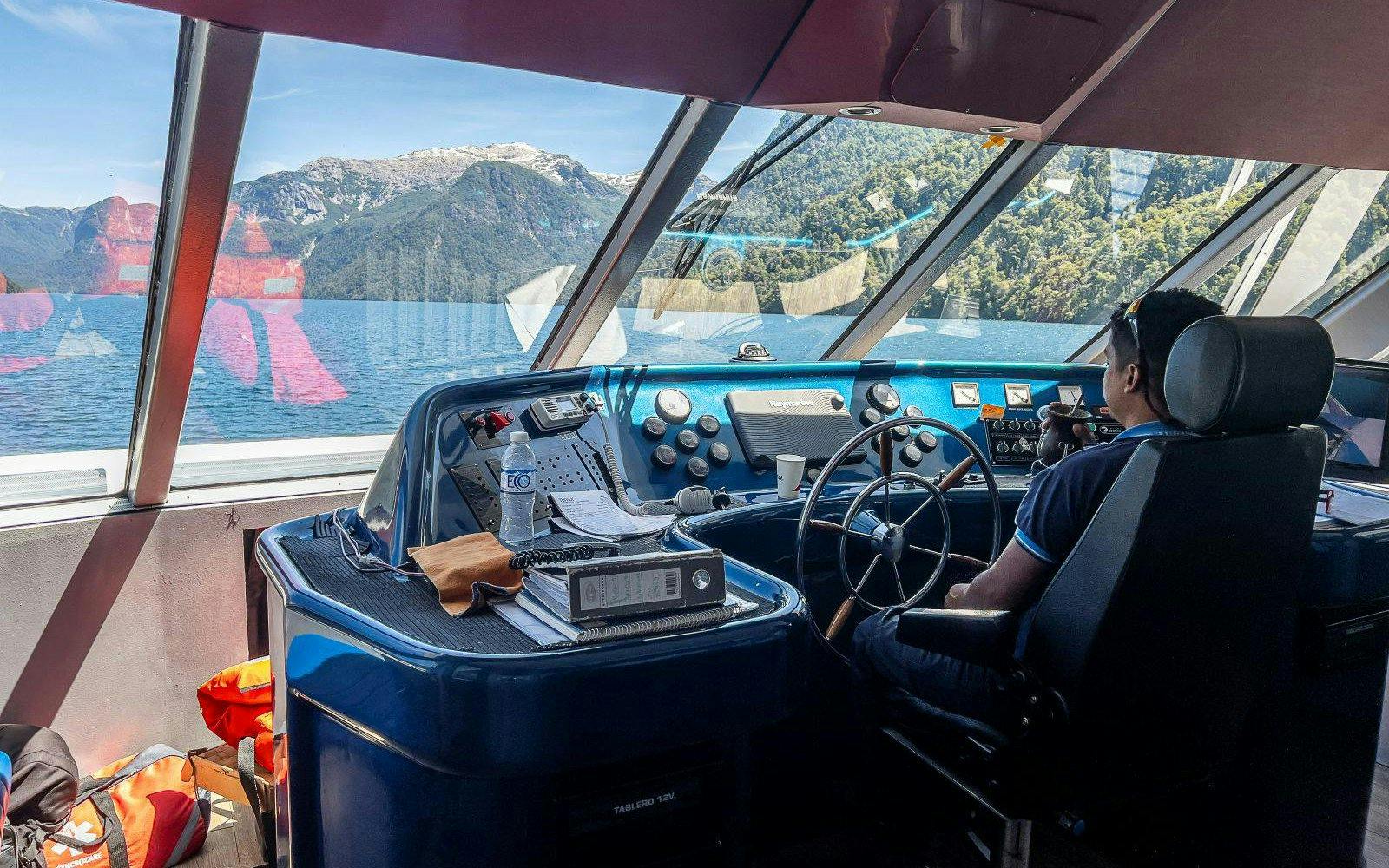 Captain steering a sightseeing boat on Nahuel Huapi Lake, Patagonia.