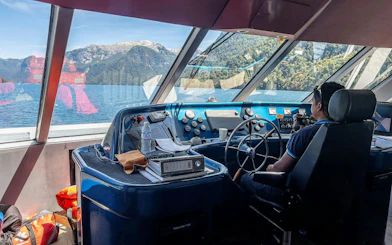 Captain steering a sightseeing boat on Nahuel Huapi Lake, Patagonia.