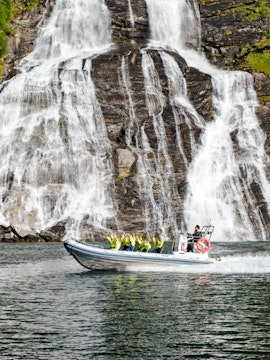 RIB boat on Geiranger Fjord near Seven Sisters waterfall during safari tour.