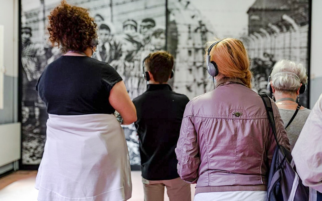 Visitors with headphones viewing Auschwitz Birkenau Memorial Museum exhibit.